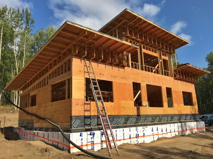 Traditional wood-framed house under construction with roof overhangs